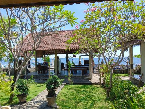 a pavilion with a table and trees in a yard at beach side Amed Delem family in Amed