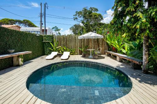 a small swimming pool on a wooden deck with an umbrella at Loft Trancoso com Piscina & Jacuzzi in Trancoso