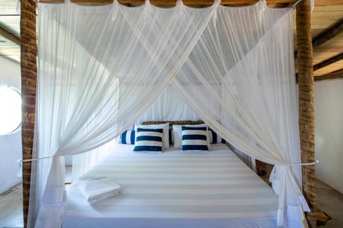 Cama blanca con dosel y almohadas azules y blancas en Loft Trancoso - casa moderna e rústica em trancoso, en Trancoso