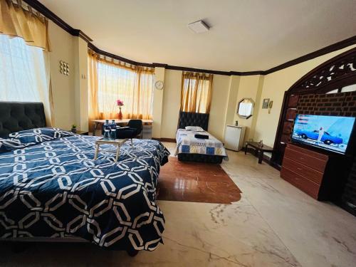 una camera da letto con un letto e una TV a schermo piatto di Mega Suite junto al San Marino Shopping a Guayaquil