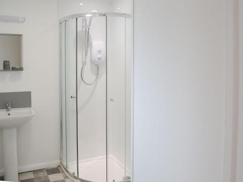 a shower with a glass door in a bathroom at Beach Cottage in Nairn