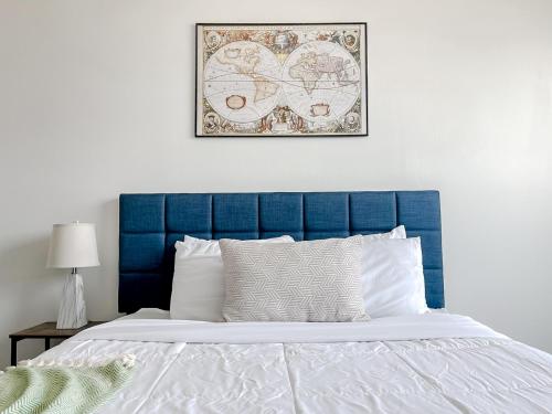 a bed with a blue headboard and a picture on the wall at Sleepover 1BD 1BA Des Moines Apartments in Des Moines