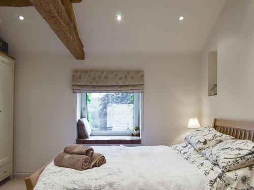 a bedroom with a bed and a window with a chair at Easter Cottage in Bamford