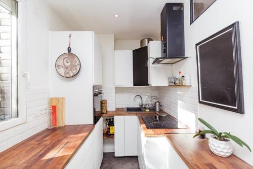 a kitchen with white cabinets and a clock on the wall at Charming 51m In Aubervilliers in Aubervilliers