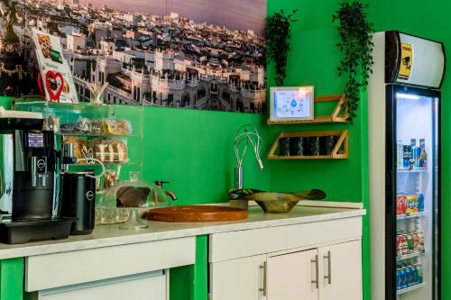 cocina con paredes verdes y encimera con fregadero en OXYGEN HOSTEL Capsula en Madrid