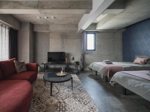 um quarto com duas camas e um sofá e uma televisão em La luna em Yomitan