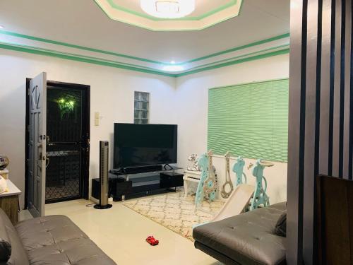 - un salon avec un canapé et une télévision dans l'établissement Holiday House near Butuan City Airport, à Butuan