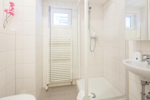 a white bathroom with a shower and a sink at Hotel Herzog in Düsseldorf