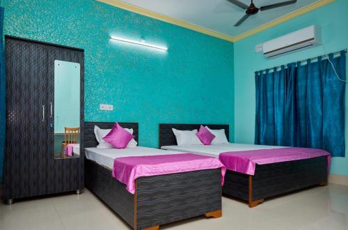 two beds in a room with blue walls and pink sheets at deb Guest House And Banquet hall in Kolkata