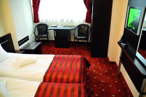 a hotel room with a bed and a table with chairs at Hotel Roberts in Sibiu