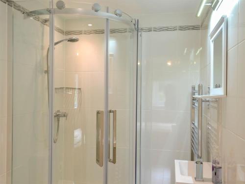 a shower with a glass door in a bathroom at Eagles Cottage in Corston