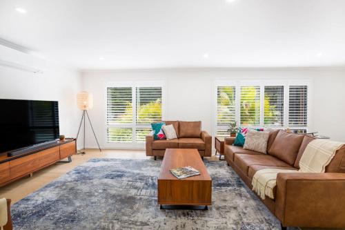 a living room with a couch and a tv at Mirigaan I Pet Friendly I 8 Min Walk to Beach in Culburra Beach
