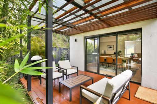 a screened in porch with white chairs and a table at Mirigaan I Pet Friendly I 8 Min Walk to Beach in Culburra Beach