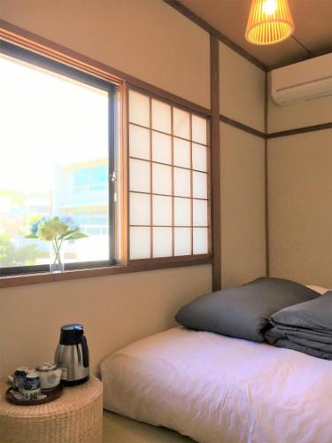 a room with a bed and a window and a table at Guesthouse Hakuka in Kanazawa