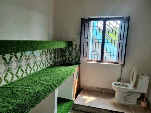ein Badezimmer mit grünen Pflanzen an den Wänden und ein WC in der Unterkunft Jim Corbett Home stay in Jhirna