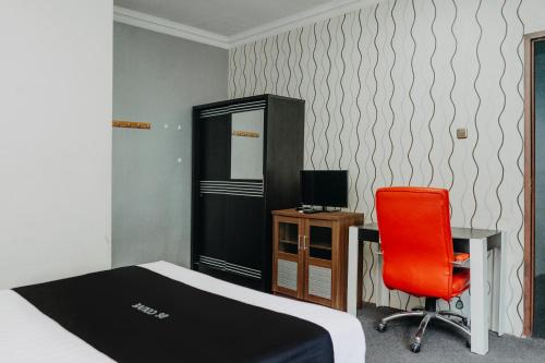 a bedroom with a bed and a desk and a red chair at DS Colive 34 in Semarang