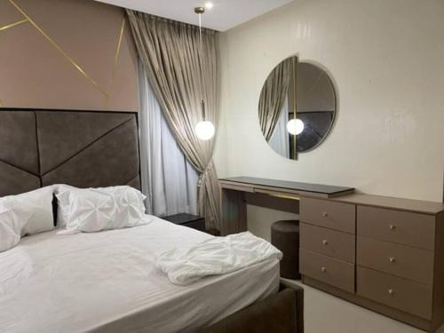 a bedroom with a bed and a mirror and a dresser at Cozy 3 bedroom flat in serene gated Ikoyi Estate in Lagos
