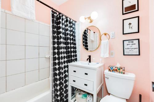a pink bathroom with a black and white shower at Soleil House - Unit C in Galveston