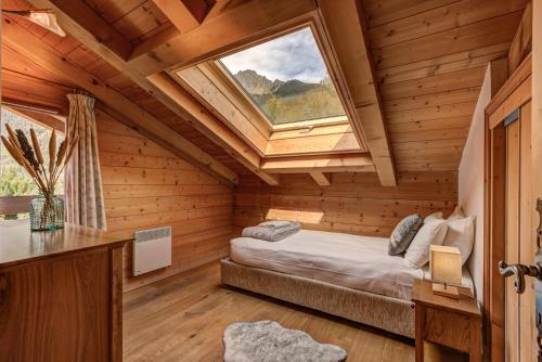La Cloche des Bois - Alpes Travel - Les Bois - Sleeps 4-6 في شامونيه مون بلان: غرفة نوم في كابينة خشب مع نافذة