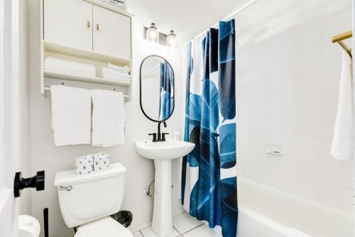 a white bathroom with a sink and a mirror at Soleil House - Unit D in Galveston