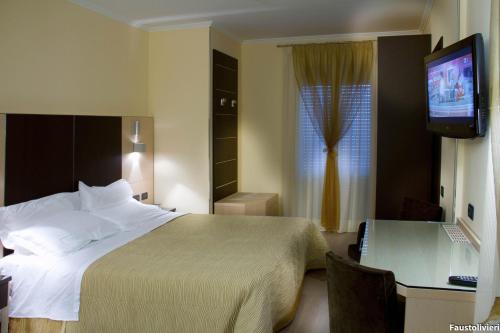 a hotel room with a bed and a desk and a television at Hotel Imperial in San Benedetto del Tronto