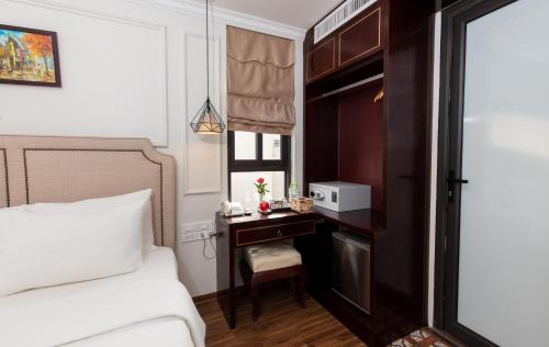 a bedroom with a bed and a desk with a chair at Golden Legend Palace Hotel & Travel in Hanoi