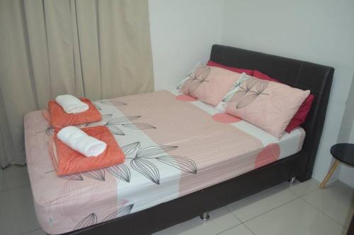 un letto con due asciugamani e cuscini sopra di Bougainvillea KintaRiverfront a Ipoh