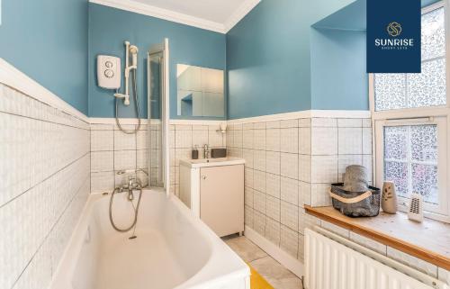 een badkamer met een wit bad en blauwe muren bij SCOTS-CORNER, Family Home, 2 Rooms, 4 Single Beds, Easy Access Ring-Road Location, Parking, WiFi, Sleeps 4, Fully Equipped, Home from Home, Brilliant Location, Beautiful River Views by SUNRISE SHORT LETS in Dundee