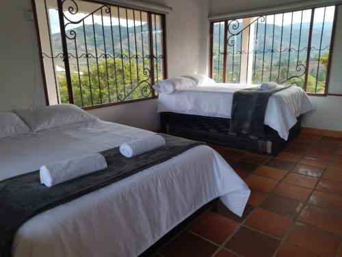 two beds in a room with two windows at Mirador de la cuesta in Tres Esquinas