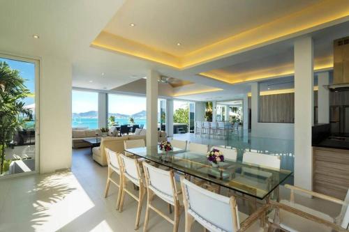 a dining room and living room with a glass table and chairs at Villa Nirvana - Beachfront Tropical Chic 4BR Haven in Cape Panwa, Phuket in Ban Ao Makham