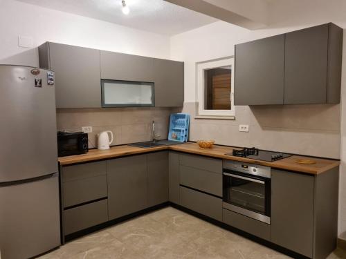 uma cozinha com armários cinzentos e um frigorífico em Apartments Ante - 50 M from the sea em Seget Vranjica
