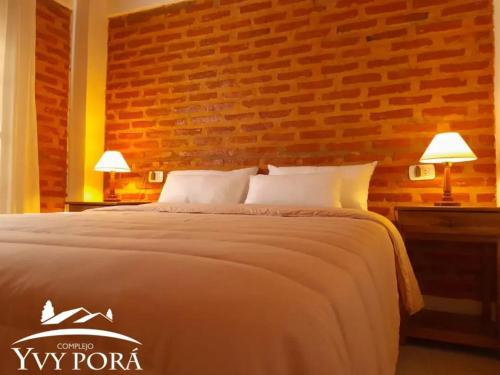 a bedroom with a large bed with a brick wall at Complejo Yvy Porá in Goya