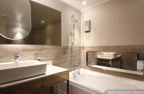 a bathroom with a sink and a tub and a mirror at Newmond Hotel in Seoul