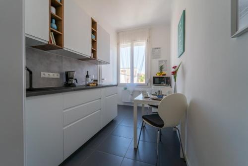 a kitchen with white cabinets and a table and a chair at Sunhill Studio in Budapest