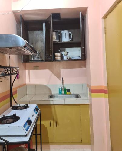 Il comprend une petite cuisine équipée d'une cuisinière et d'un évier. dans l'établissement Affordable Condo for Rent near Emperor Events Place, à Cainta