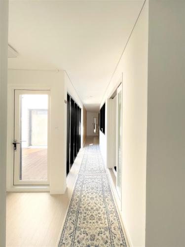 a hallway with white walls and a patterned rug at Koin Guesthouse Incheon airport in Incheon