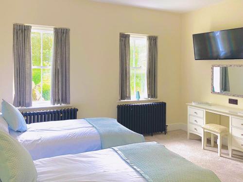 1 dormitorio con 2 camas, escritorio y 2 ventanas en Heath View, en Cheddleton
