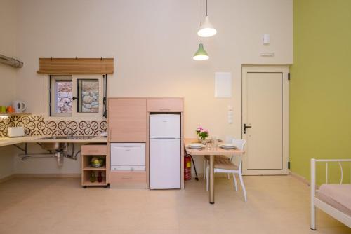 a kitchen with a table and a white refrigerator at Aksos Suites Accessible Accommodation in Ayiá