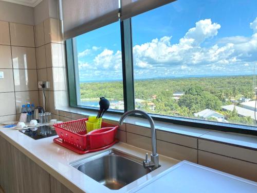 a kitchen sink with a red basket next to a window at The Lanes Hotel in Tutong