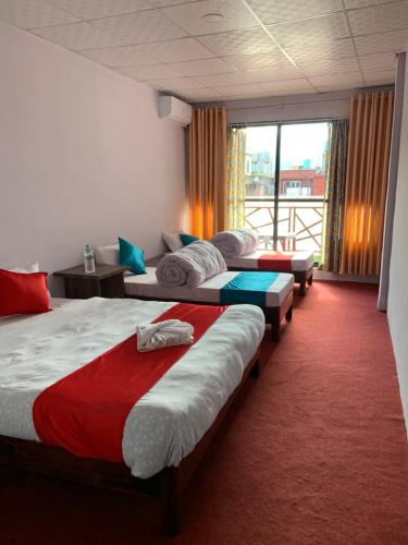 a hotel room with two beds and a balcony at Hotel Good One in Pokhara
