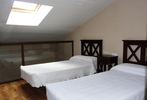 a bedroom with two beds and a skylight at Apartamentos Valle&Snow in Vallejera de Riofrío