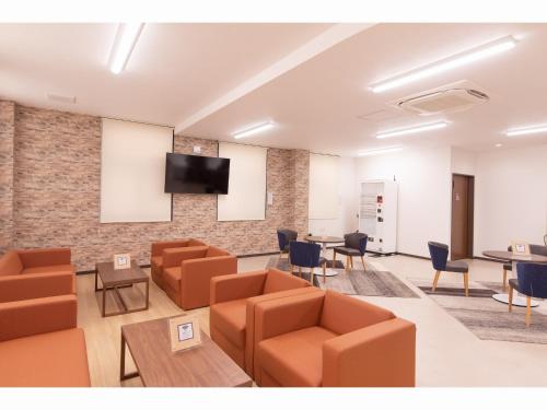 a waiting room with couches and a tv on a brick wall at Hotel FRENTE HIRONO in Hirono