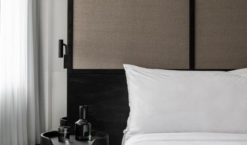 a bed with a white pillow and a bottle on a table at Lancemore Crossley St. Melbourne in Melbourne