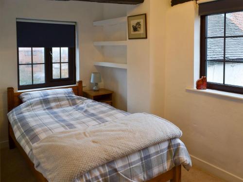 a bedroom with a bed and two windows at Ikkle Cottage in Blidworth