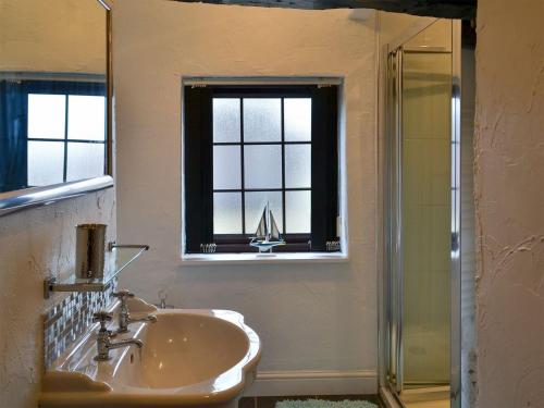 a bathroom with a sink and a window and a shower at Ikkle Cottage in Blidworth