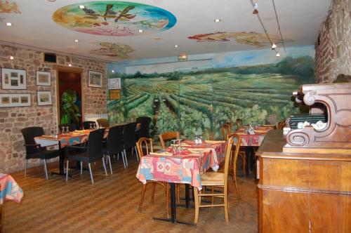 a restaurant with tables and chairs and a mural at Hôtel Restaurant La Belle Epoque in Le Creusot