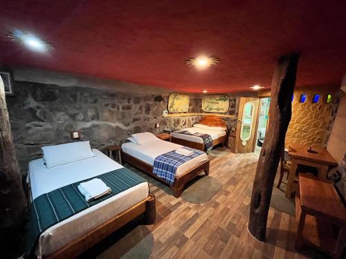 1 dormitorio con 2 camas y pared de piedra en Lonesome George Ecolodge, en Puerto Ayora