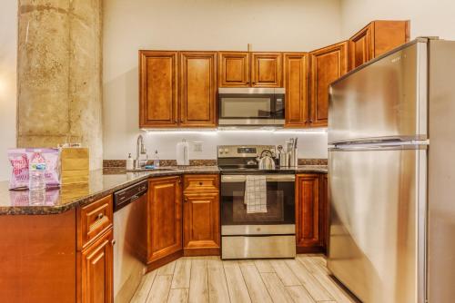 a kitchen with wooden cabinets and a stainless steel refrigerator at Sosuite at Independence Lofts - Callowhill in Philadelphia