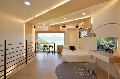 a bedroom with a bed and a balcony with a view at Tongyeong Amusing Story in Tongyeong