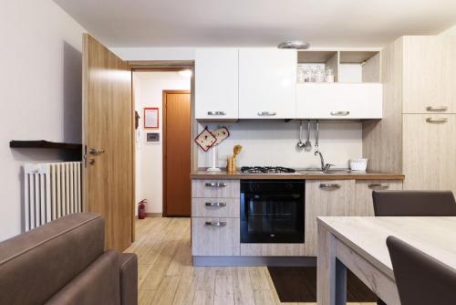 uma cozinha com armários brancos e um forno com placa de fogão em Cambrembo a 3km da foppolo casa x6persone con Camino e Wifi em Valleve